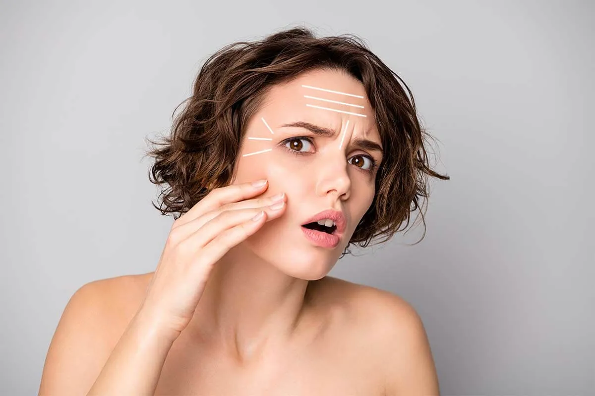 Baby Botox preventivo arrugas Mujer joven preocupada observando arrugas faciales para Baby Botox preventivo