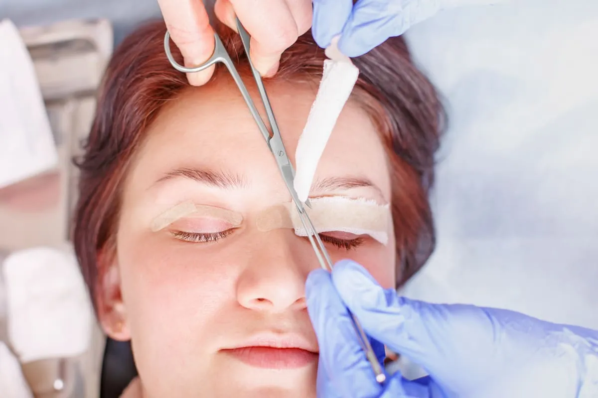 Paciente tras cirugía de blefaroplastia con apósitos en párpados