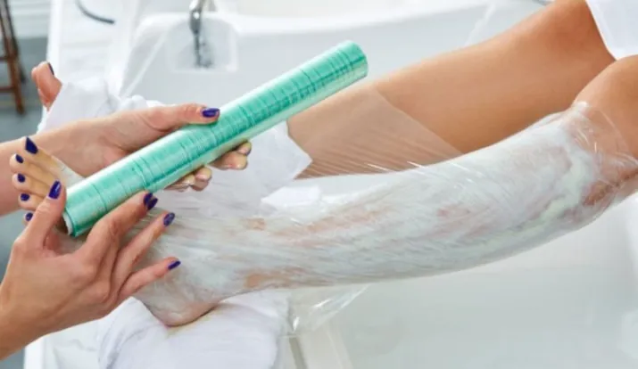 Crema anestésica con film Aplicación de envoltura plástica en pierna con crema anestésica para depilación láser