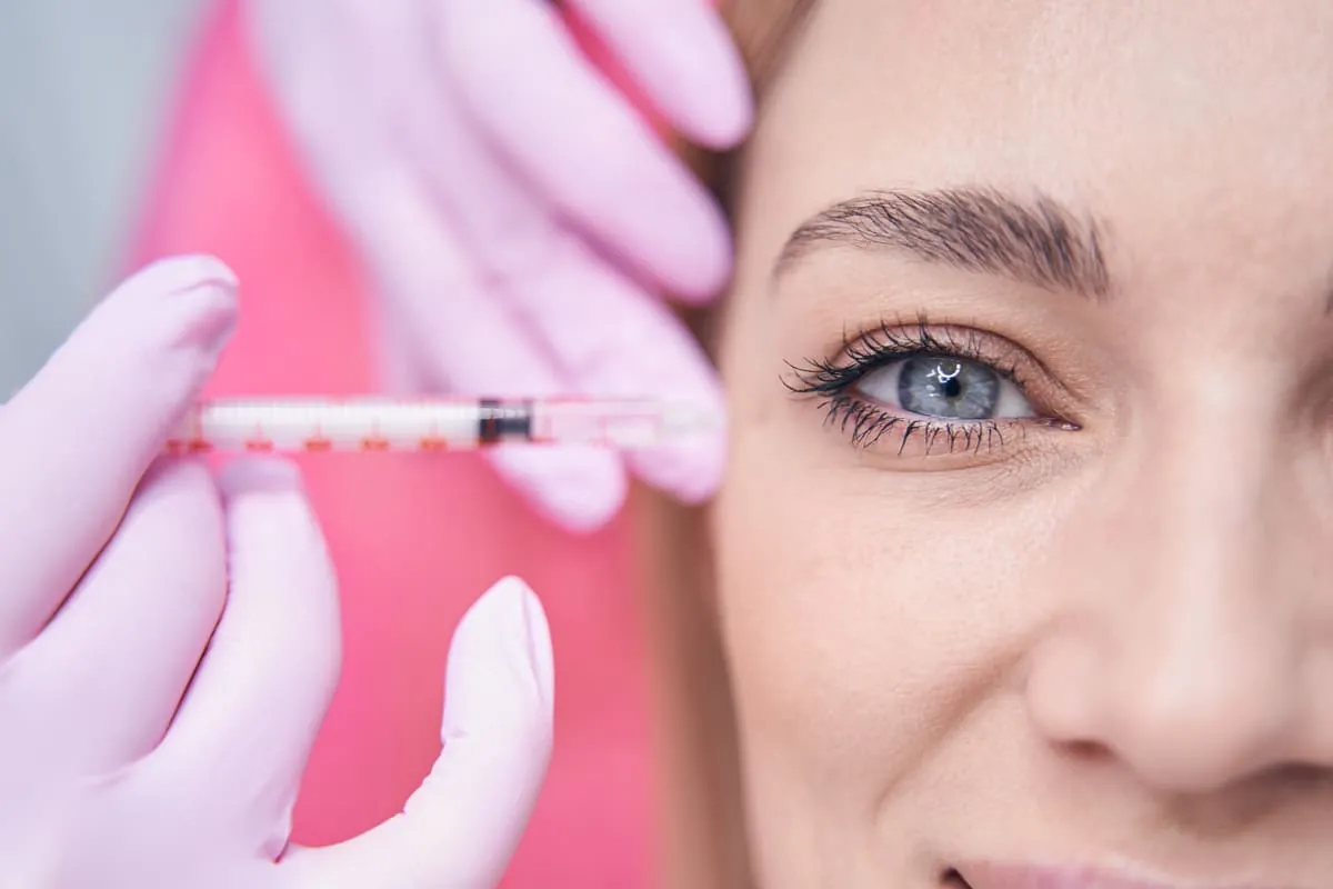 Tratamiento facial con Ellansé Mujer recibiendo inyección de Ellansé o Radiesse en el contorno ocular
