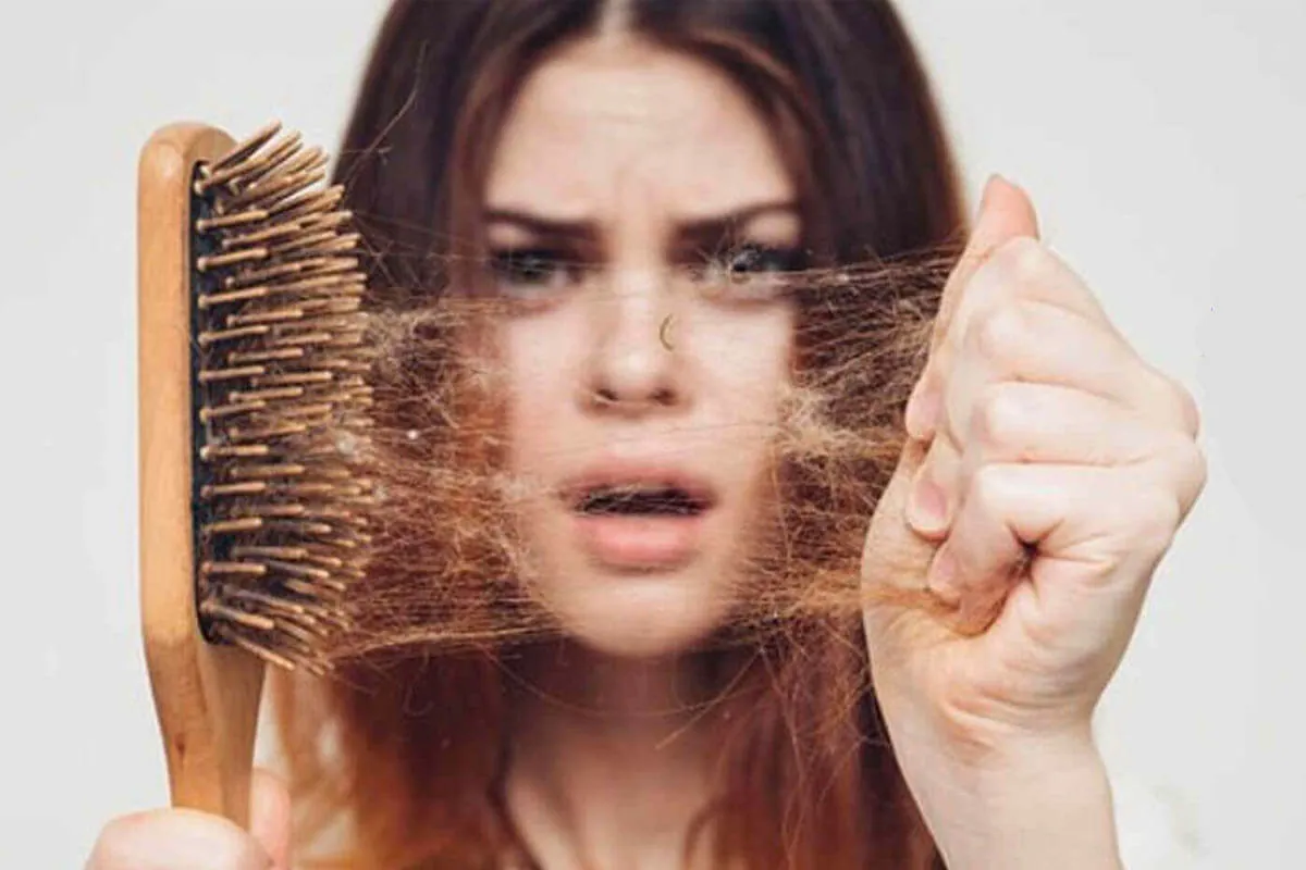 Caída del pelo y ronquina Mujer preocupada mostrando caída del pelo en el cepillo tras peinarse